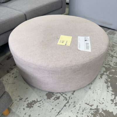 EX STAGING HIRE - LIGHT GREY ROUND MATERIAL OTTOMAN SOLD AS IS