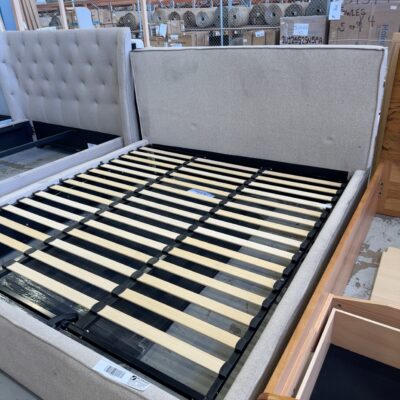 SAMPLE FURNITURE - STEVIE KING BEDFRAME, BEIGE UPHOLSTERY, DARK GREASE STAIN ON TOP LEFT OF BEDFRAME, SOLD AS IS